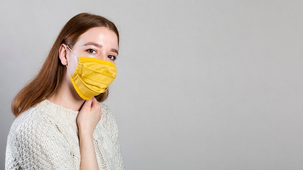 Kostenloses Foto seitenansicht der frau, die eine medizinische maske mit kopienraum trägt