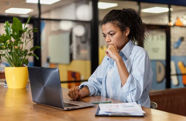 Seitenansicht der Frau, die im Büro mit Laptop arbeitet