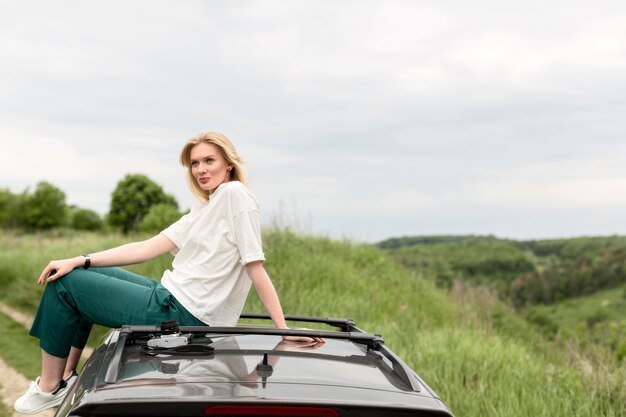 Seitenansicht der Frau, die in der Natur oben auf Auto aufwirft