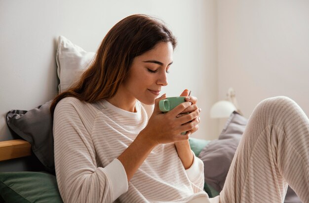 Seitenansicht der Frau, die Kaffee im Bett hat