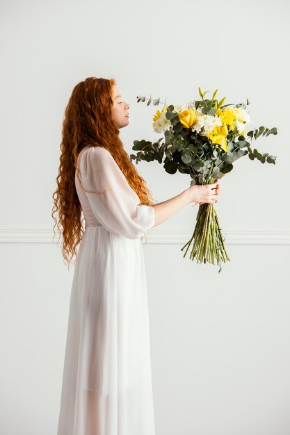 Seitenansicht der Frau, die mit Blumenstrauß der Frühlingsblumen aufwirft