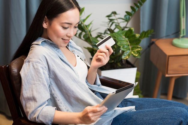 Seitenansicht der Frau, die online mit Tablette und Kreditkarte bestellt