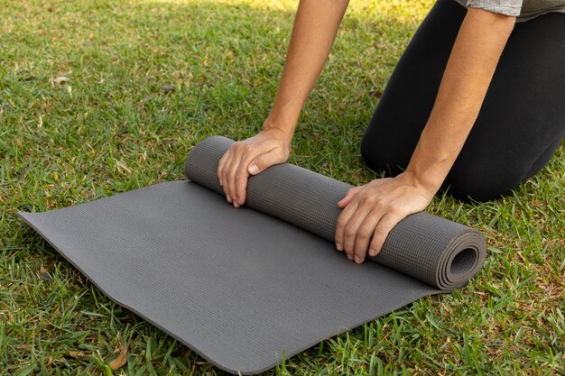 Seitenansicht der Frau, die Yogamatte auf dem Gras rollt