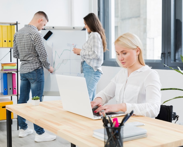 Seitenansicht der Frau im Rollstuhl, die im Büro arbeitet