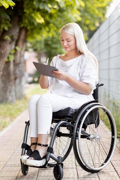 Seitenansicht der Frau im Rollstuhl mit Tablette