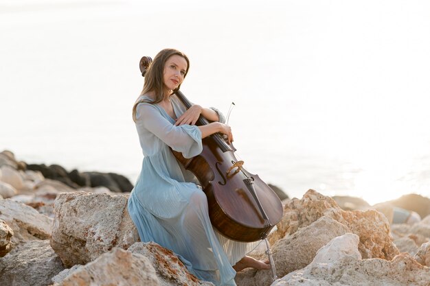 Seitenansicht der Frau mit Cello auf Felsen