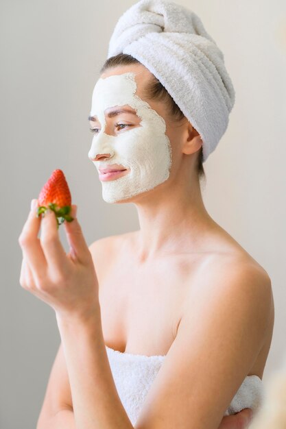 Seitenansicht der Frau mit Gesichtsmaske, die Erdbeere hält