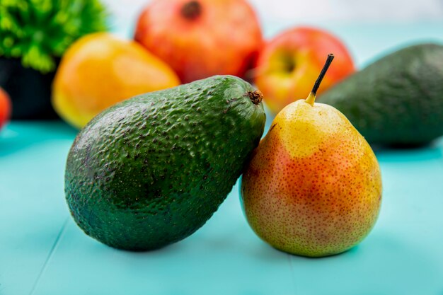 Seitenansicht der frischen und grünen Avocado mit Birne auf blauer Oberfläche