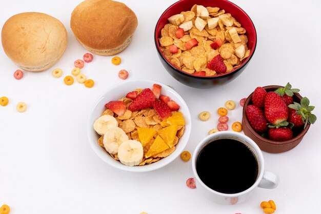 Seitenansicht der Frühstücks-Cornflakes mit Erdbeere und Kaffee auf weißer Fläche horizontal