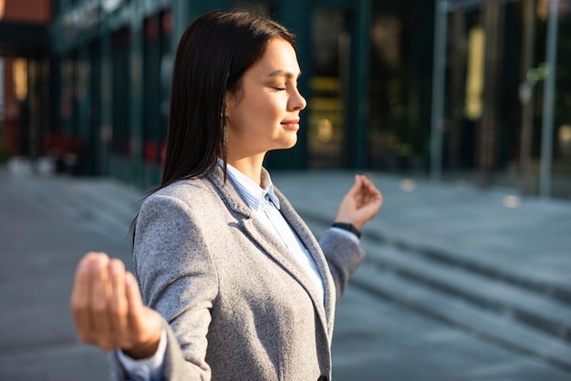 Kostenloses Foto seitenansicht der geschäftsfrau in zen-pose in der stadt