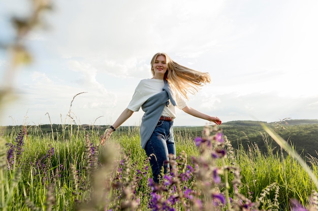 Kostenloses Foto seitenansicht der glücklichen frau, die durch feld aufwirft