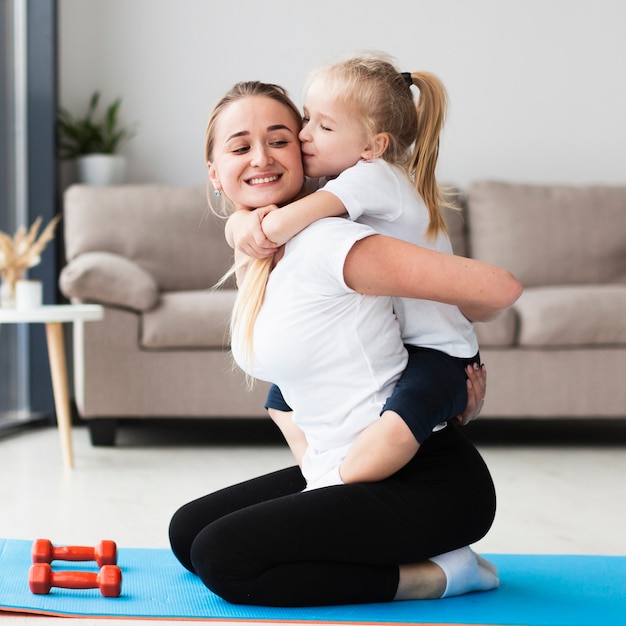 Seitenansicht der glücklichen Mutter und Tochter, die während des Trainings aufwerfen