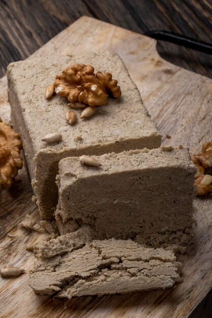 Seitenansicht der Halva mit Sonnenblumenkernen und Walnüssen auf einem Holzbrett