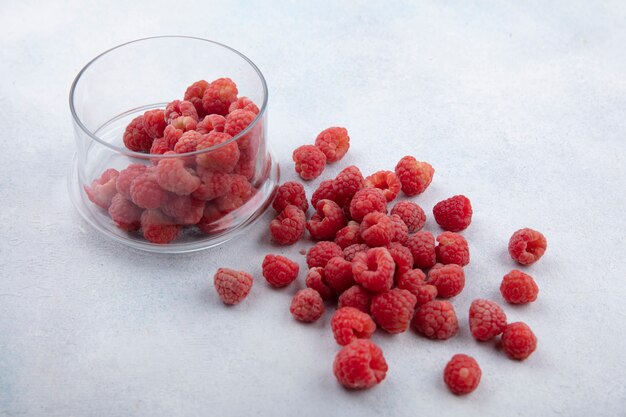 Seitenansicht der Himbeeren in der Glasschale und auf Weiß