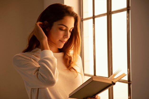 Seitenansicht der jungen Frau, die ein Buch zu Hause liest