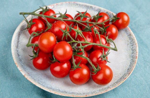 Seitenansicht der kleinen Tomaten im Teller auf blauem Tisch