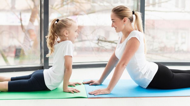 Seitenansicht der Mutter auf Yogamatte zu Hause mit Tochter
