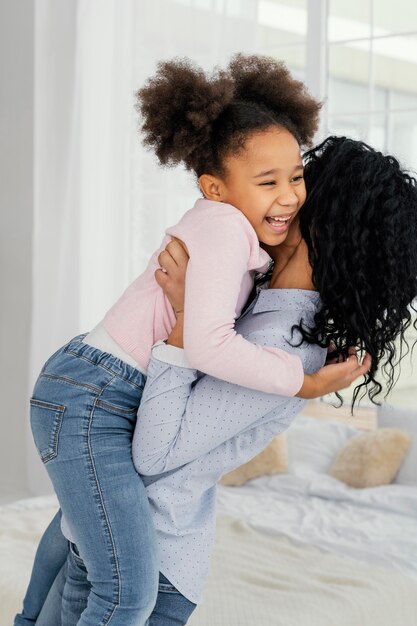 Seitenansicht der Mutter, die ihre Smiley-Tochter hält