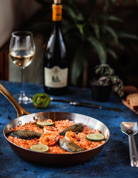 Seitenansicht der Paella mit Muscheln und Garnelen in der Pfanne auf Blau