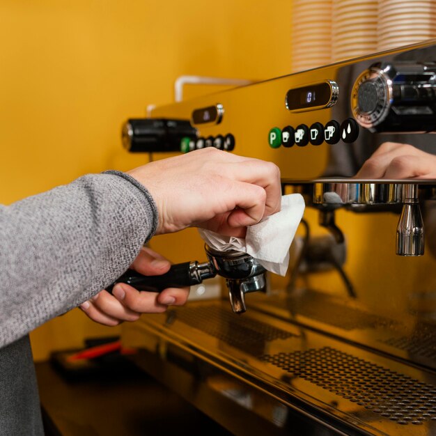 Seitenansicht der professionellen Kaffeemaschine der männlichen Barista-Reinigung