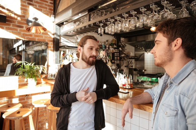 Seitenansicht der ruhigen Freunde, die nahe der Bar stehen