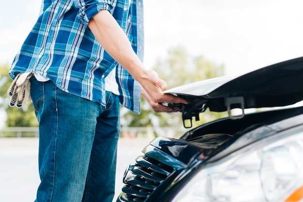 Seitenansicht der schließenden Autohaube des Mannes