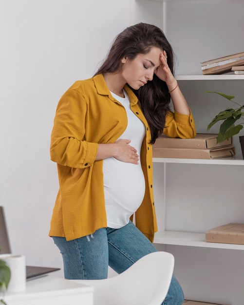 Seitenansicht der schwangeren Frau zu Hause, die sich nicht sehr gut fühlt