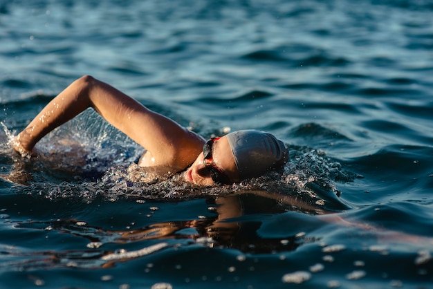 Seitenansicht der Schwimmerin mit Mütze und Schutzbrille, die im Wasser schwimmen