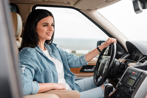 Seitenansicht der Smiley-Frau, die allein mit dem Auto reist