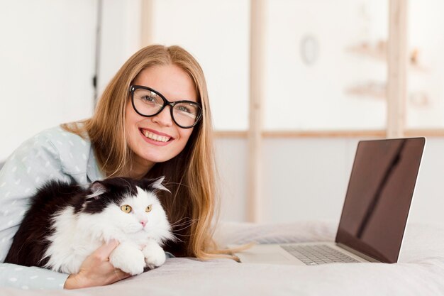 Seitenansicht der Smiley-Frau im Pyjama von zu Hause im Bett mit Bett