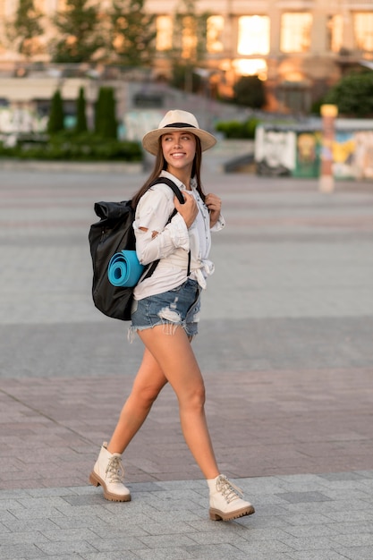 Seitenansicht der Smileyfrau mit Hut, der Rucksack trägt, während sie alleine reist