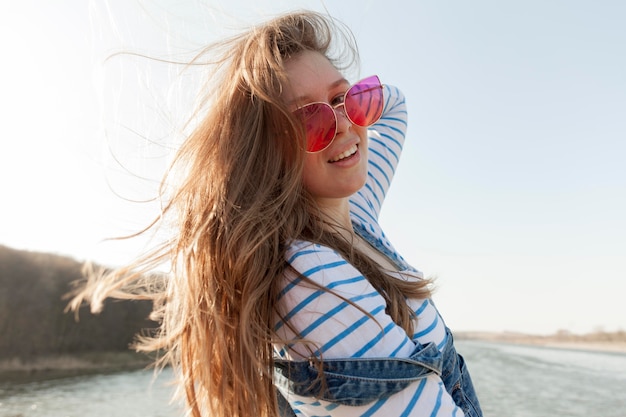 Seitenansicht der sorglosen Frau, die mit Sonnenbrille durch den See aufwirft