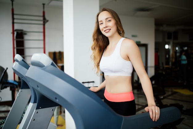 Seitenansicht der sportlichen Frau, die auf Laufband im Fitnessstudio ausübt