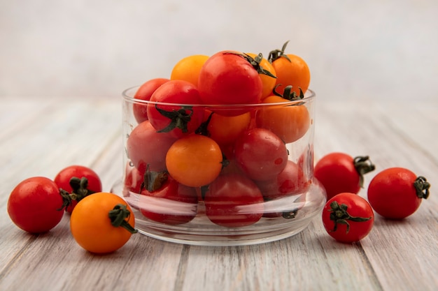 Seitenansicht der süßen frischen roten Tomaten auf einer Glasschale auf einer grauen Holzoberfläche