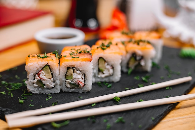 Seitenansicht der Sushi-Rolle der traditionellen japanischen Küche mit Lachskrabbenfleisch-Avocado und Frischkäse auf Tafel