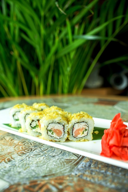 Seitenansicht der Sushi-Rolle der traditionellen japanischen Küche mit Thunfisch, serviert mit Ingwer auf Grün