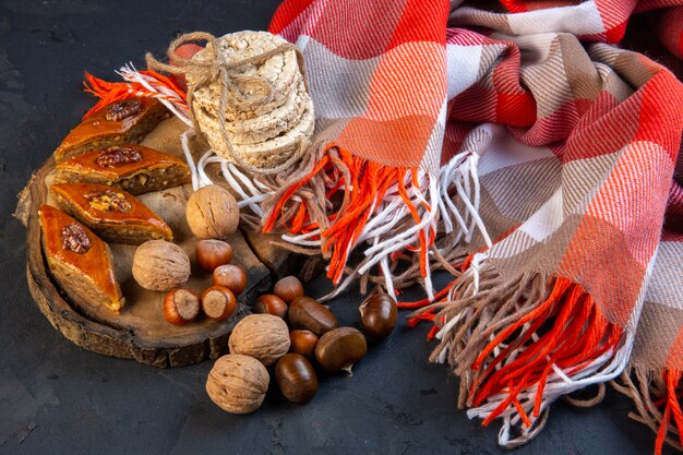 Seitenansicht der traditionellen aserbaidschanischen Baklava mit ganzen Nüssen und Reisbrot auf Plaid mit Quaste