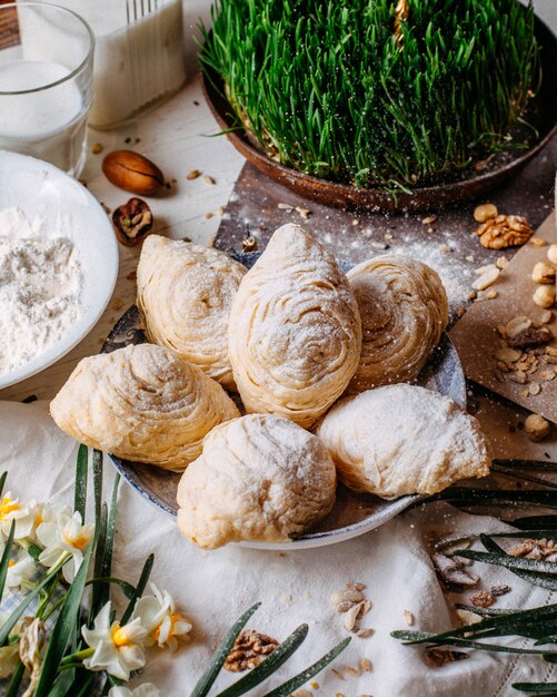 Seitenansicht der traditionellen aserbaidschanischen Feiertagsplätzchen shekerbura auf dem rustikalen mit Nüssen