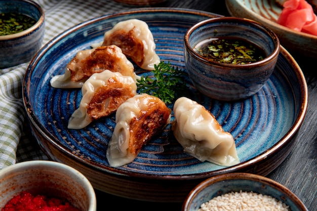 Seitenansicht der traditionellen asiatischen knödel mit fleisch und gemüse, die mit sojasauce auf einem teller auf rustikal serviert werden