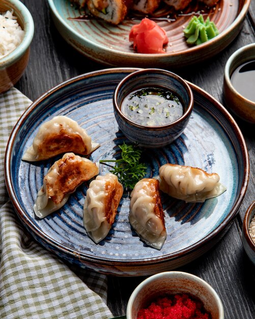 Seitenansicht der traditionellen asiatischen Knödel mit Fleisch und Gemüse, die mit Sojasauce auf einem Teller auf rustikal serviert werden