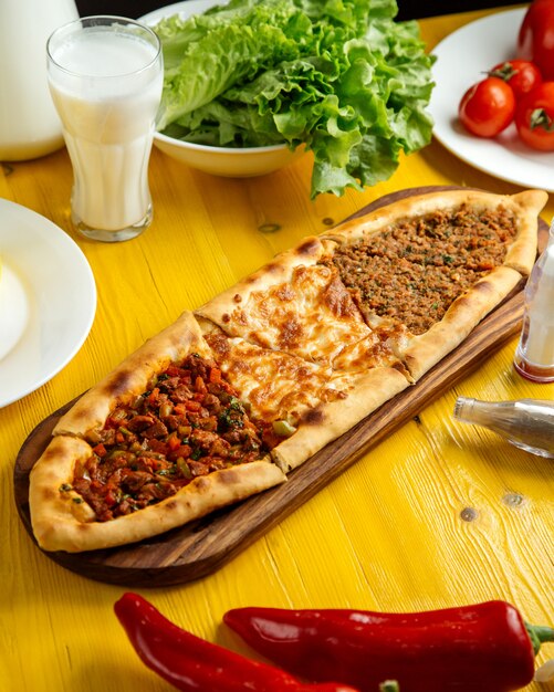 Seitenansicht der traditionellen türkischen Küche türkische Pizza Pita Pide mit einer anderen Füllung Fleischkäse Scheiben Kalbfleisch und Gemüse auf Holztisch