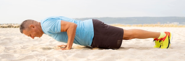 Kostenloses Foto seitenansicht des älteren mannes, der am strand arbeitet