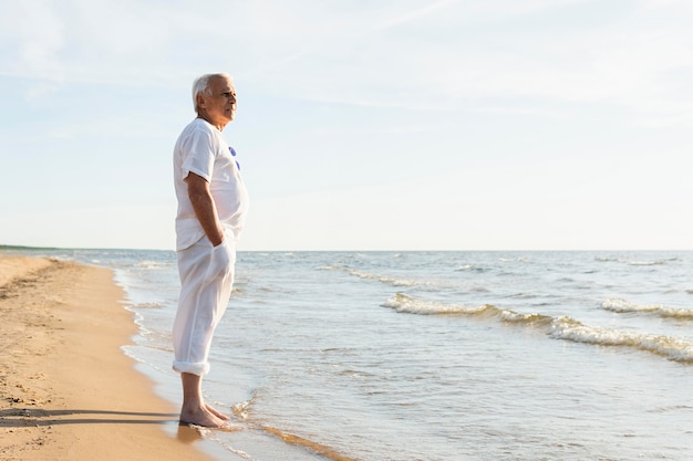 Seitenansicht des älteren Mannes, der die Ansicht am Strand genießt