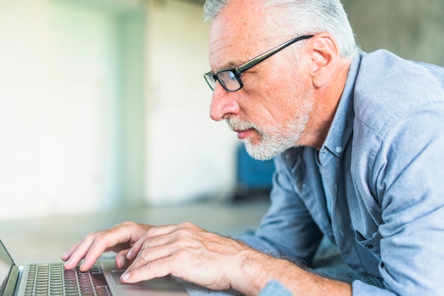 Seitenansicht des älteren Mannes, der Laptop verwendet