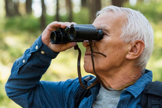 Seitenansicht des älteren Mannes draußen mit Fernglas