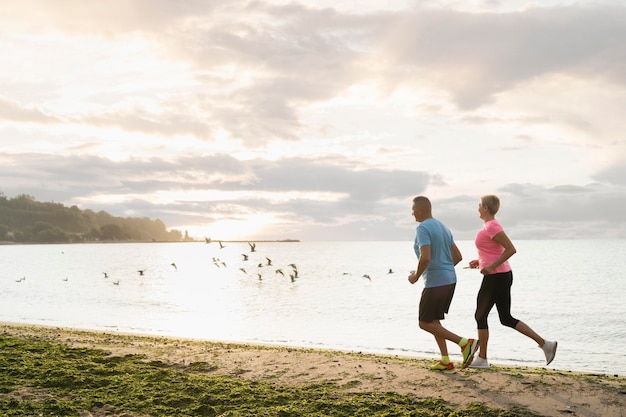 Seitenansicht des älteren Paares, das am Strand joggt