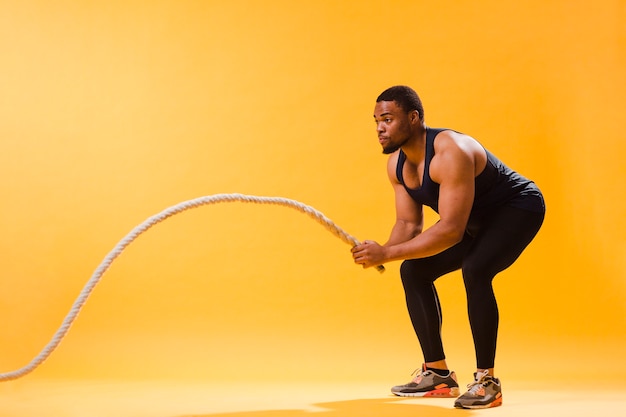 Kostenloses Foto seitenansicht des athletischen mannes seil ausübend