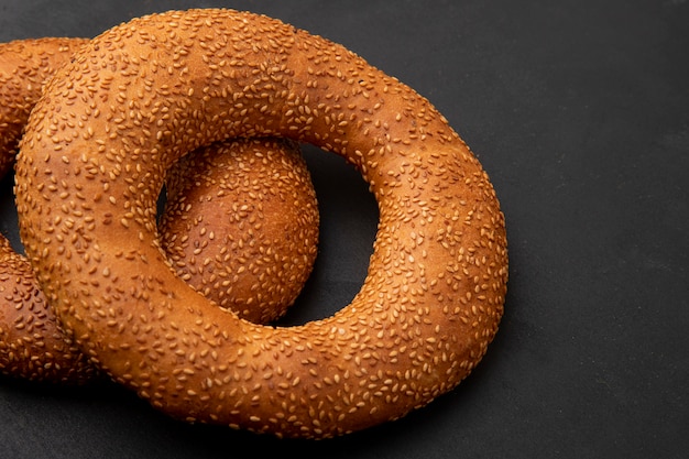 Seitenansicht des Bagels auf der linken Seite und schwarzem Hintergrund mit Kopienraum