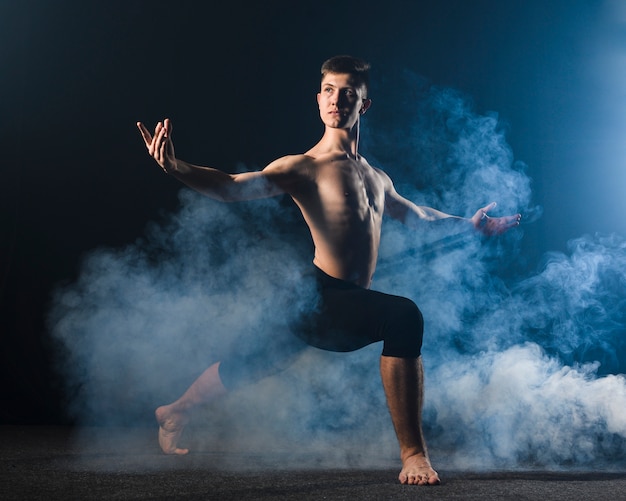 Seitenansicht des Ballerinos in den Strumpfhosen, die im Rauche aufwerfen