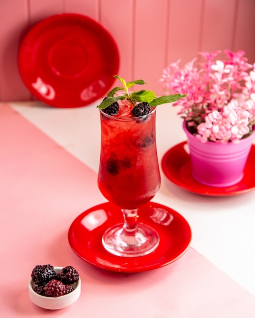 Seitenansicht des Beerencocktails mit gehacktem Eis und Minze in einem Glas auf Rosa